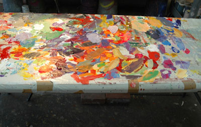 Painting table with colorful palette of paint skins on stretched plastic sheet